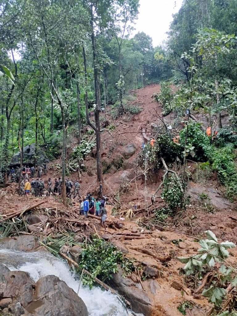 Army and NDRF personnel clear debris caused by a landslide during search and rescue operations at a flood-affected area