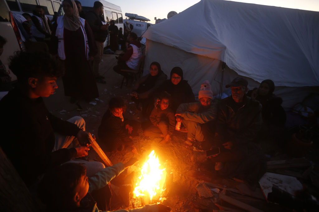 Palestinians, who were forcibly displaced as a result of Israel's attacks on the Gaza Strip for more than 15 months, try to get warm by lighting fire as they continue to wait at a point close to the Netzarim Corridor on al-Rashid Street to return to their homes in the north after the completion of the second phase of the ceasefire agreement on January 26, 2025 in Gaza City, Gaza. Photo by Ashraf Amra/Anadolu via Getty Images