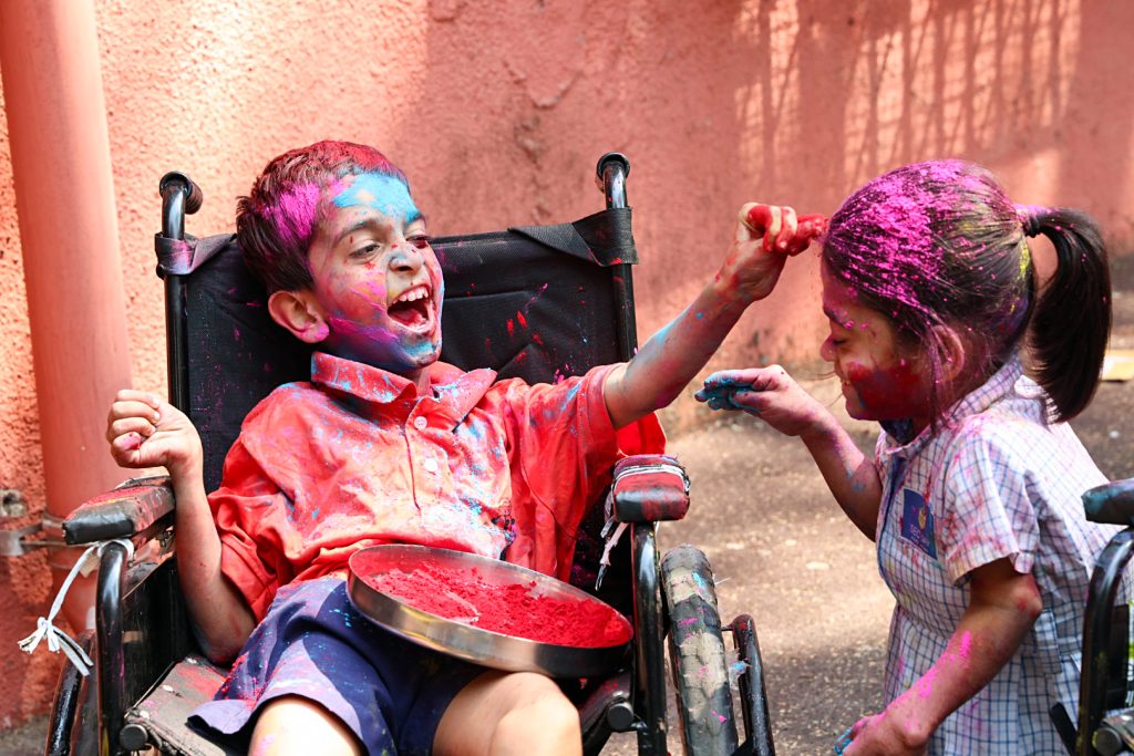 A specially abled boy applies colour to a girl as they celebrate ahead of the Holi festival