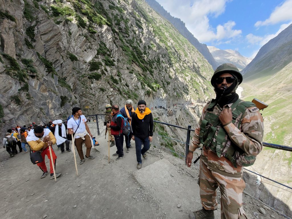 Security personnel stand guard as pilgrims arrive during Shri Amarnath Yatra