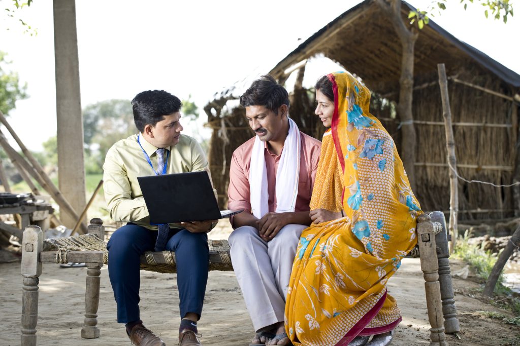 Businessman using laptop and explaining to rural couple