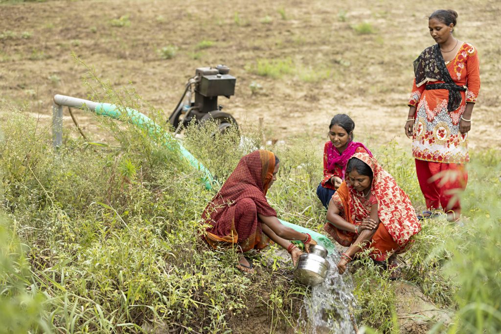 Four women filling drinking water at farm